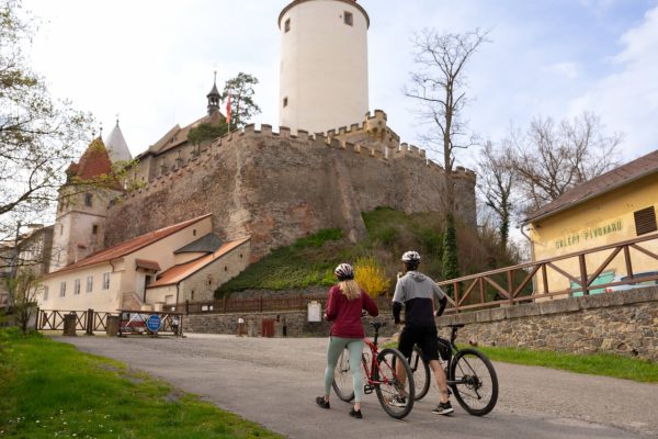Cyklisté jdoucí k hradu Křivoklát kolem sklepů pivovaru